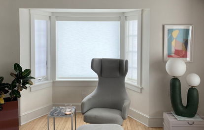 A bay window features white light-filtering roller shades