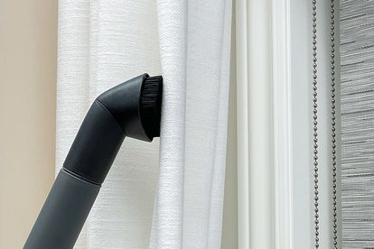 A vacuum attachment is used to clean curtains