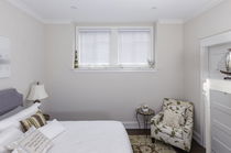 Custom wood blinds in a bedroom with two small windows, offering the look of real wood and durable light control.